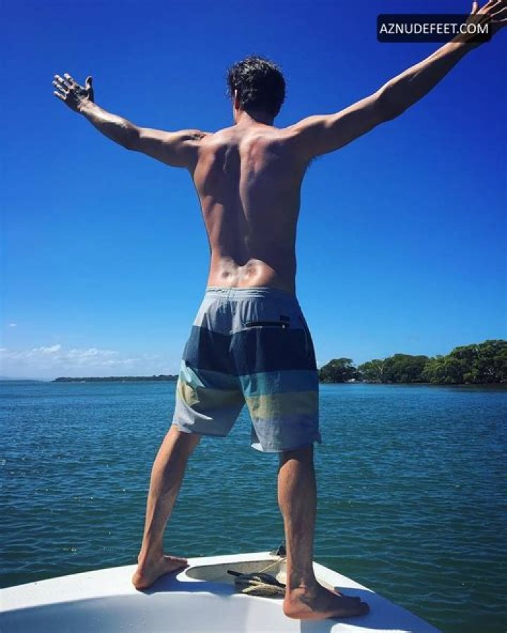 Daniel Lissing posing barefoot on sand larger surfaces