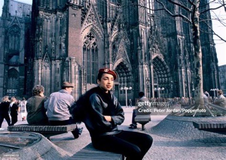 Sade Adu posing in front of a car.